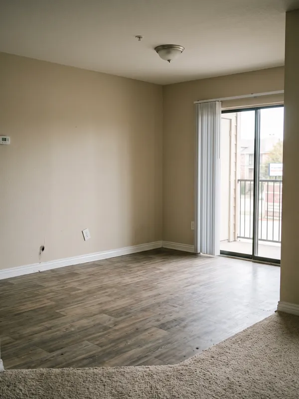 An empty apartment living room with the balcony door open
