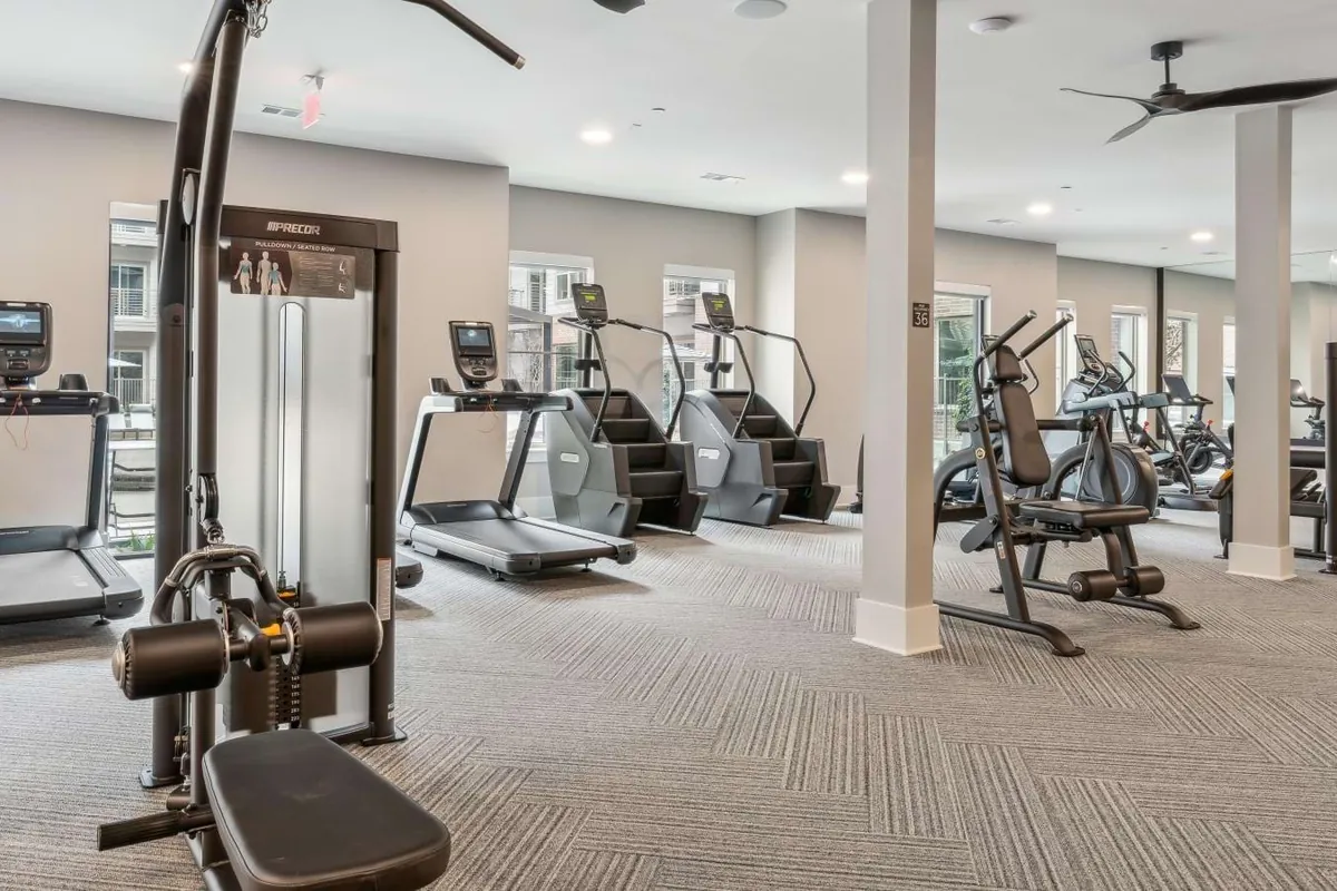 Alta Park Central in Dallas: fitness center with cardio machines and a cable weight station under a ceiling fan