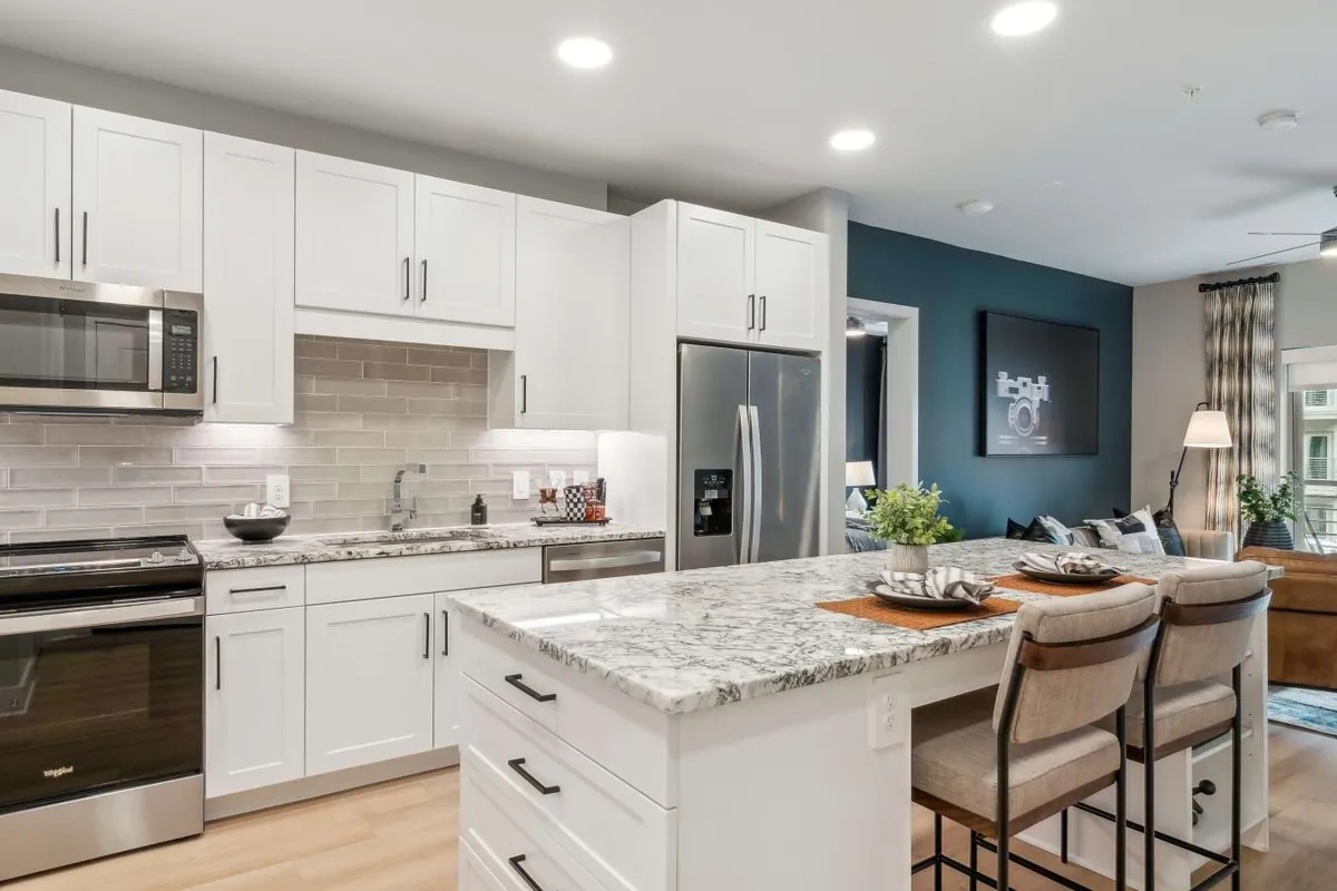 Alta Park Central in Dallas: kitchen with white cabinets, a granite island with stools, stainless appliances and a teal accent wall