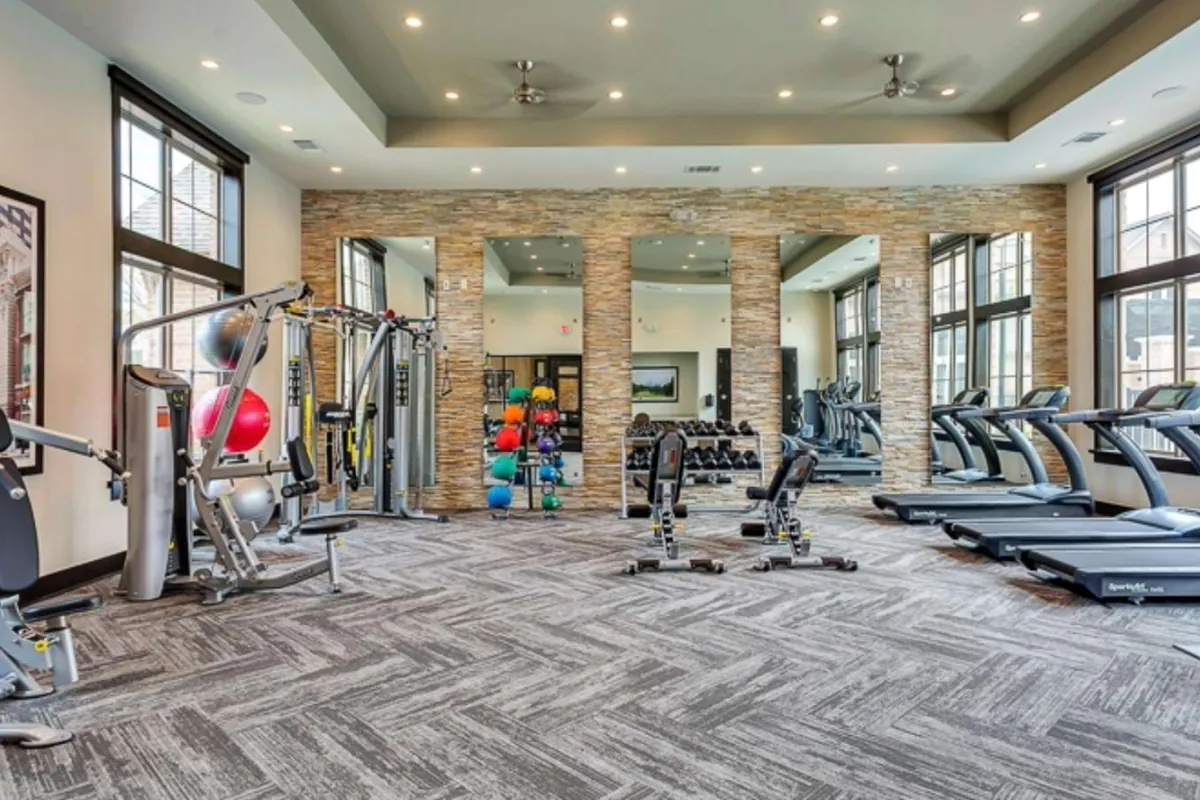 Axis Kessler Park in Dallas: fitness center with treadmills, weight machines and a stone accent wall