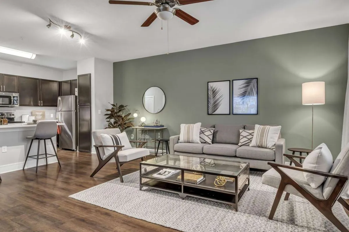 Axis Kessler Park in Dallas: living room with wood-look floors, a sofa and two armchairs, open to the kitchen