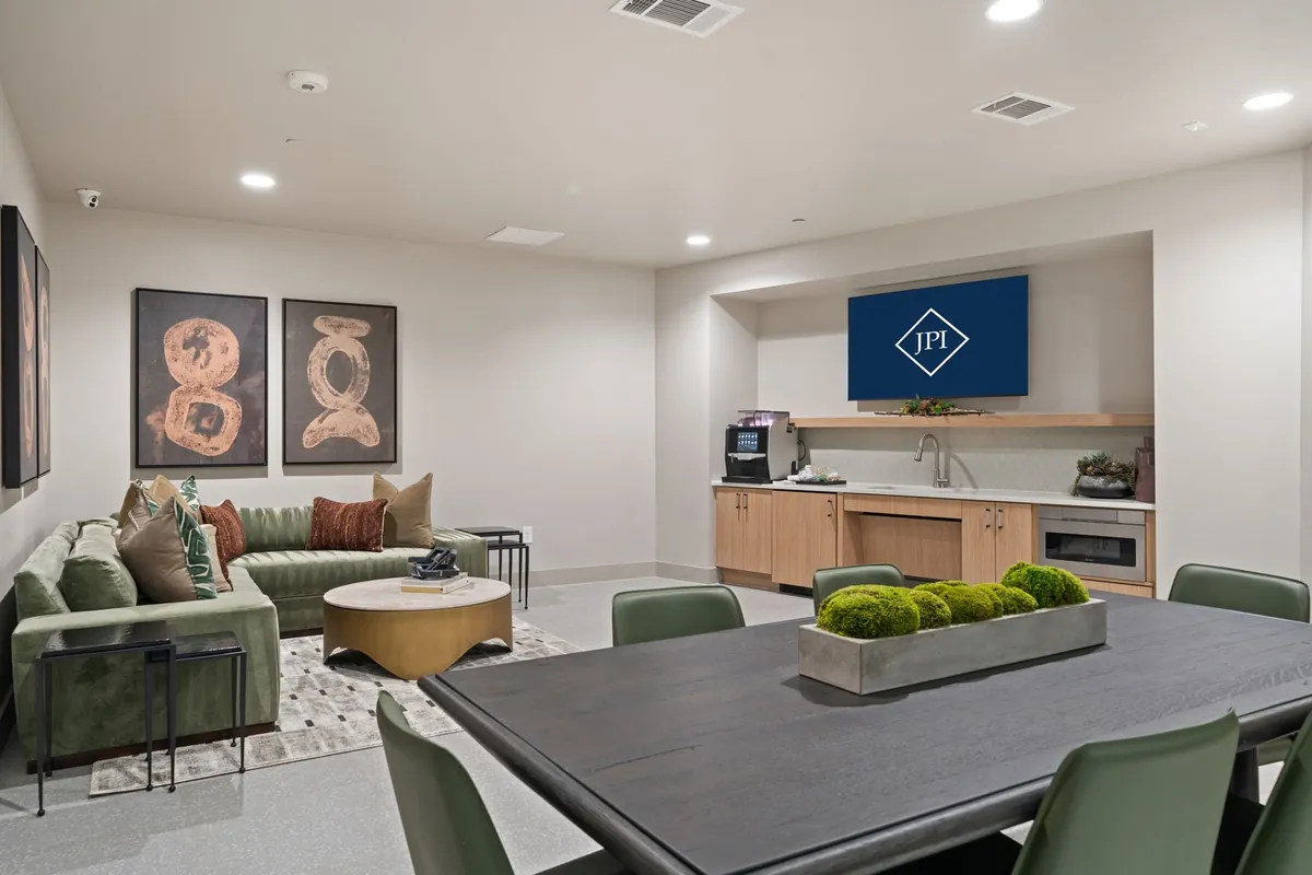 Jefferson Union at Castle Hills Marketplace in Lewisville: resident clubroom with a green sofa, a long dining table with green chairs and a coffee counter