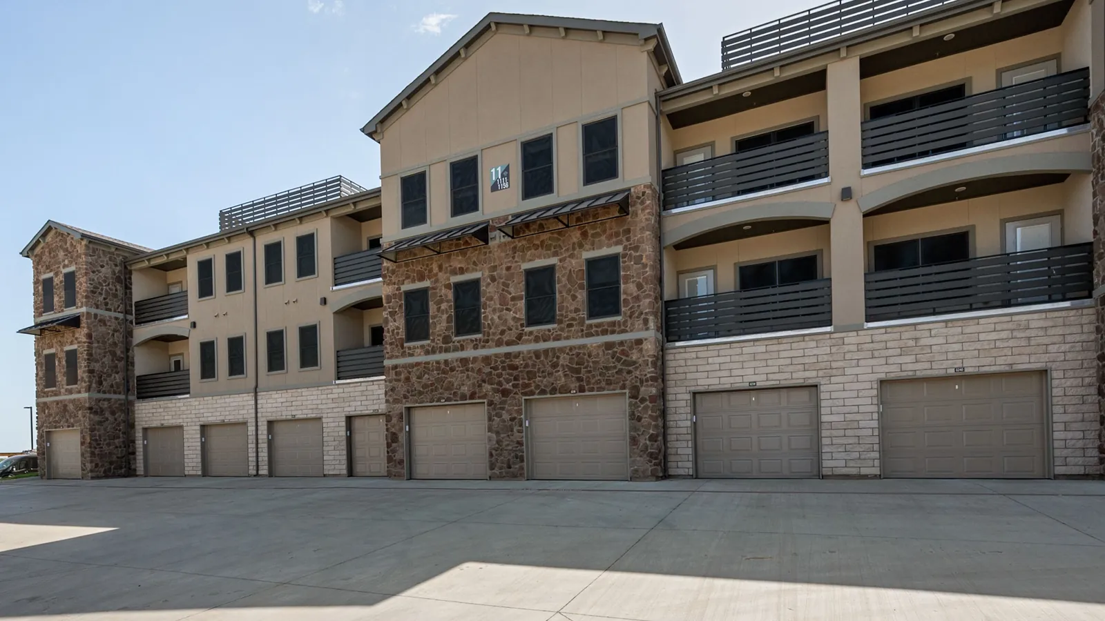 Prairie Gate Community in Grand Prairie: three-story stone and stucco apartment building with private garages on the ground floor and balconies above