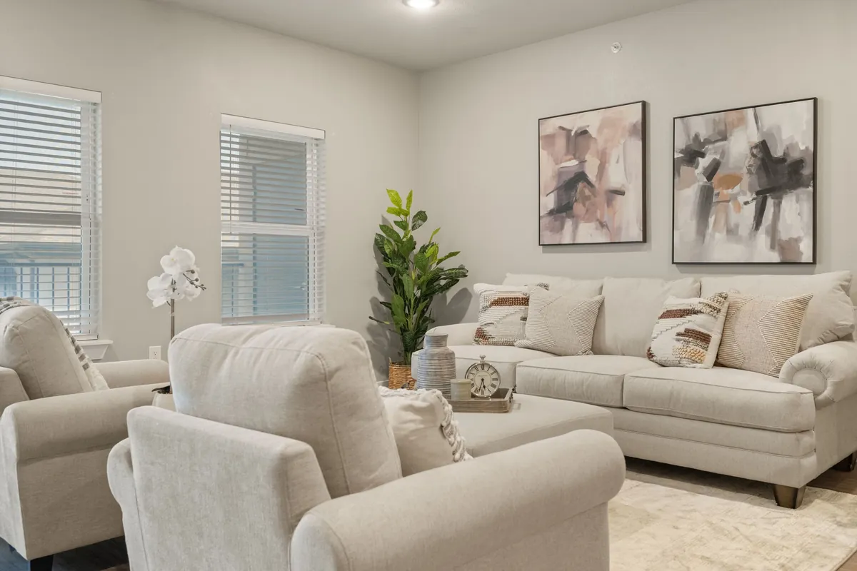 Prairie Gate Community in Grand Prairie: living room with a cream sofa, two armchairs, framed abstract art and windows with blinds