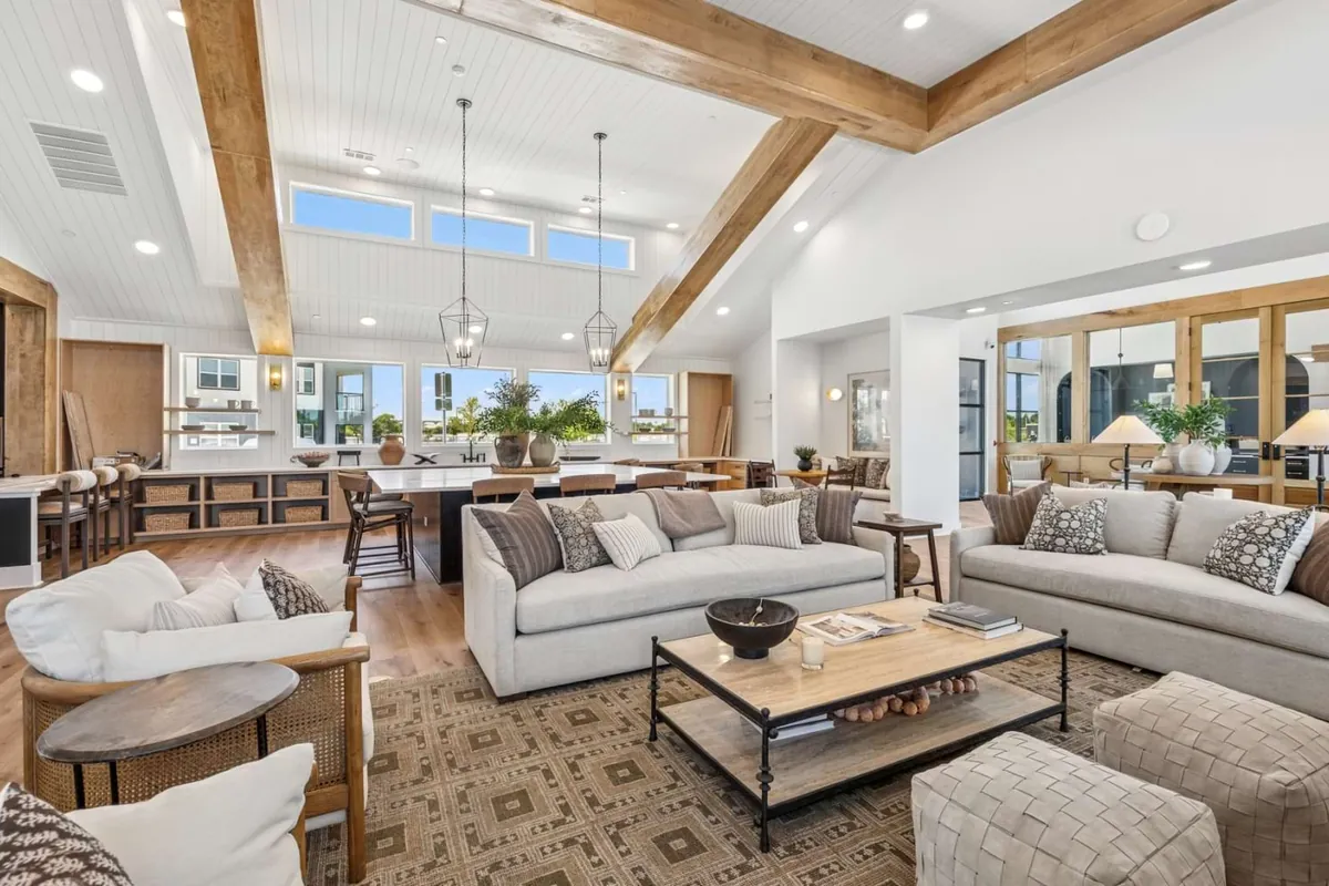 The Dalton in McKinney: clubhouse lounge with white sofas, a wood coffee table and exposed wood beams under a vaulted ceiling