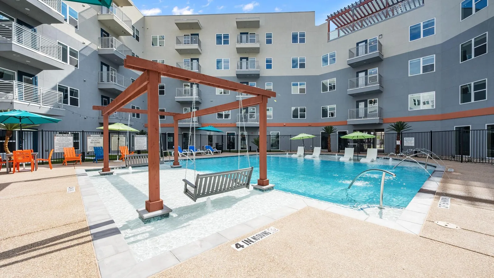 The Gibson in Grand Prairie: swimming pool with a red pergola swing and loungers in a courtyard surrounded by five-story apartment buildings